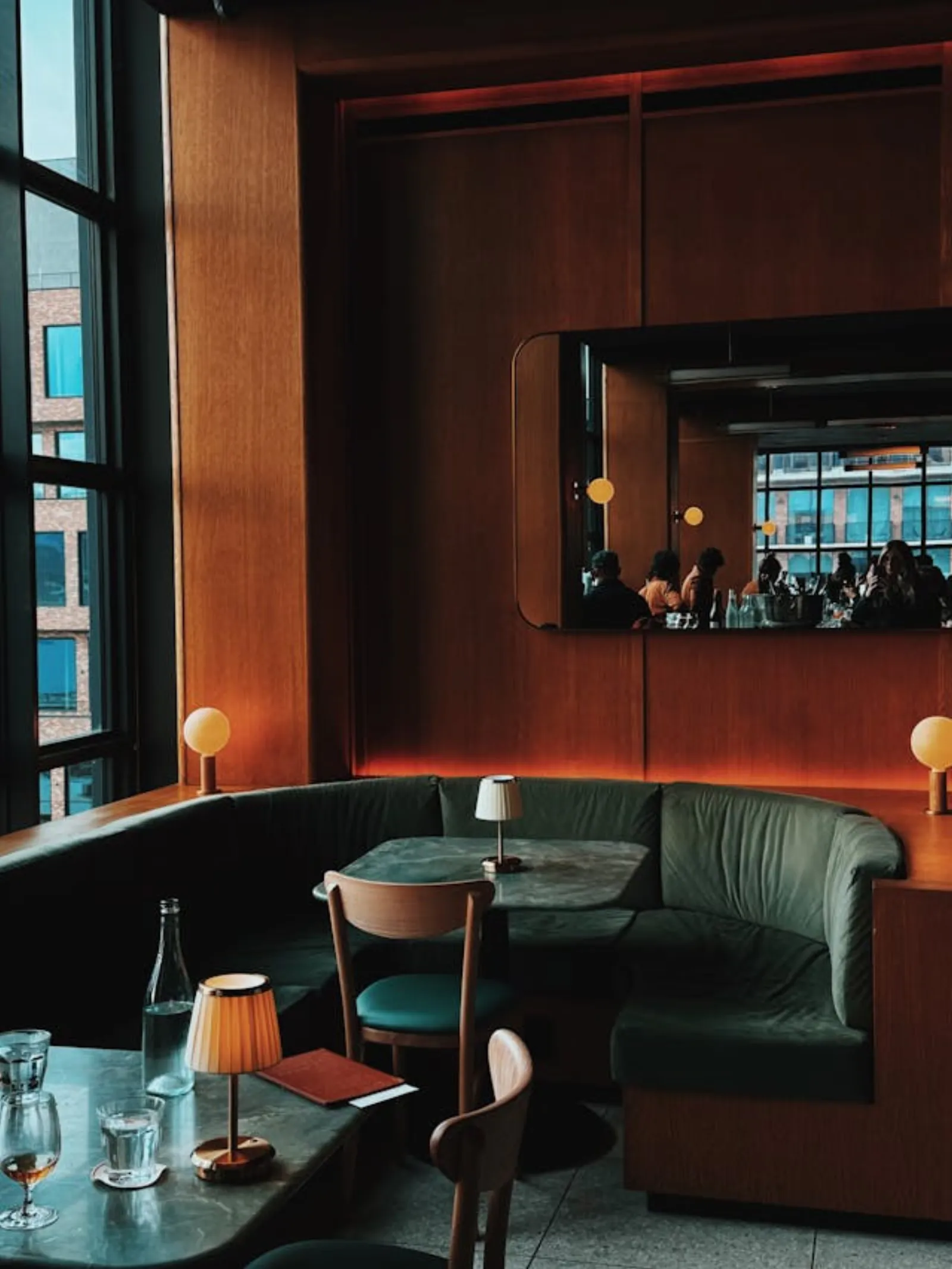 Editorial hospitality interior — warm-lit bar with banquette seating, evening atmosphere